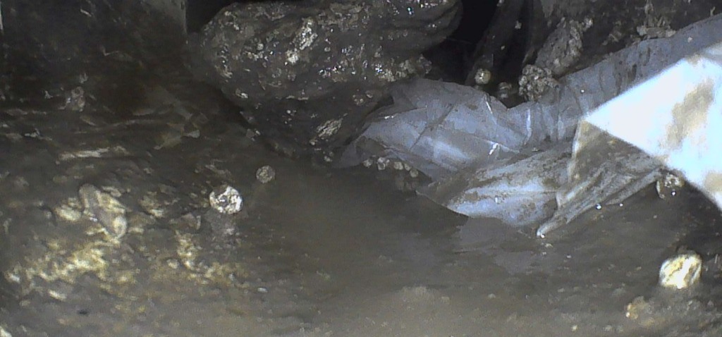 Escombros y bolsas con agua estancada dentro de un colector